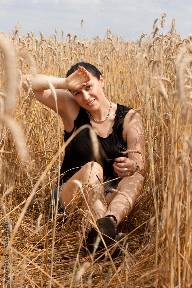 Tired young female sitting in a wheat field Tired young female sitting in a wheat field