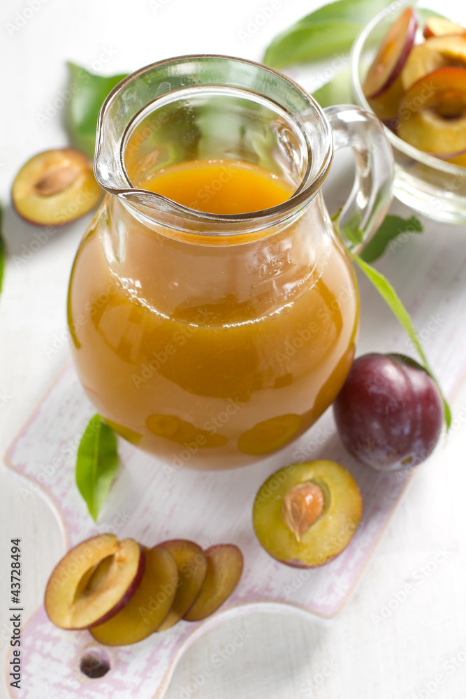 Plum juice and fresh fruits with leaves Plum juice and fresh fruits with leaves