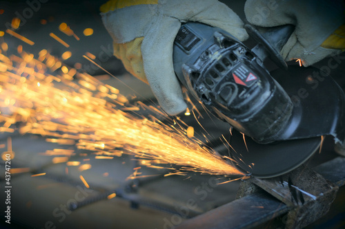 Worker cutting metal with many sharp sparks