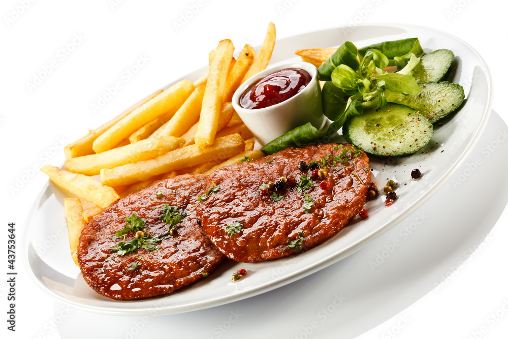 Grilled steaks, French fries and vegetables Grilled steaks, French fries and vegetables