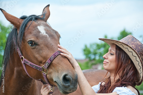 Beautiful brunette girl stroking a horse