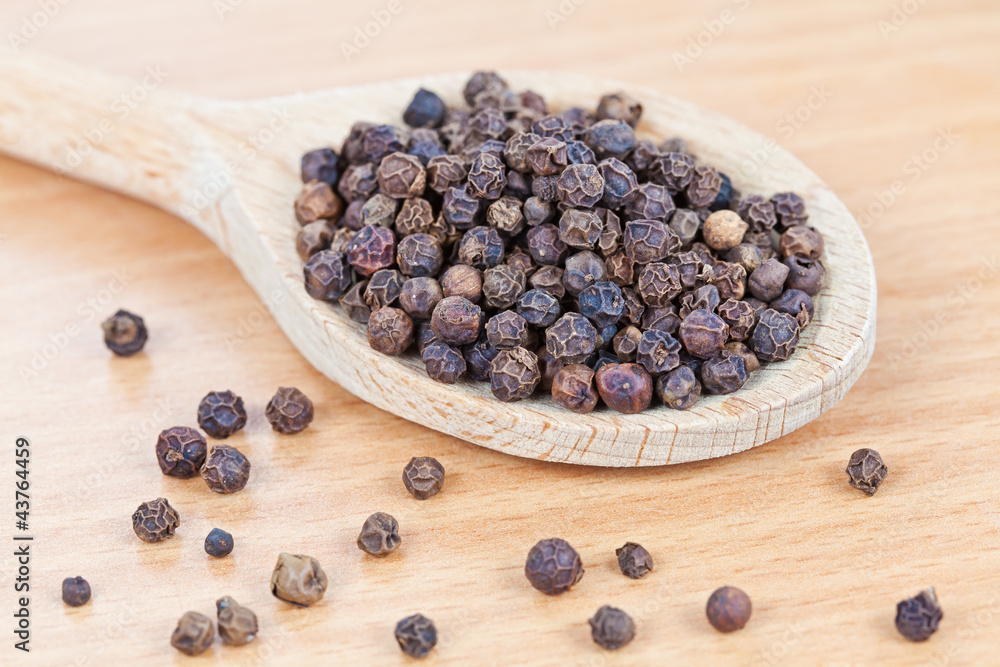 Wooden spoon filled with pepper on the kitchen board Wooden spoon filled with pepper on the kitchen board