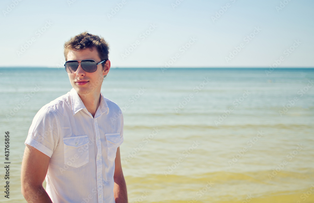 Handsome young guy on the beach, with the sea in the background
