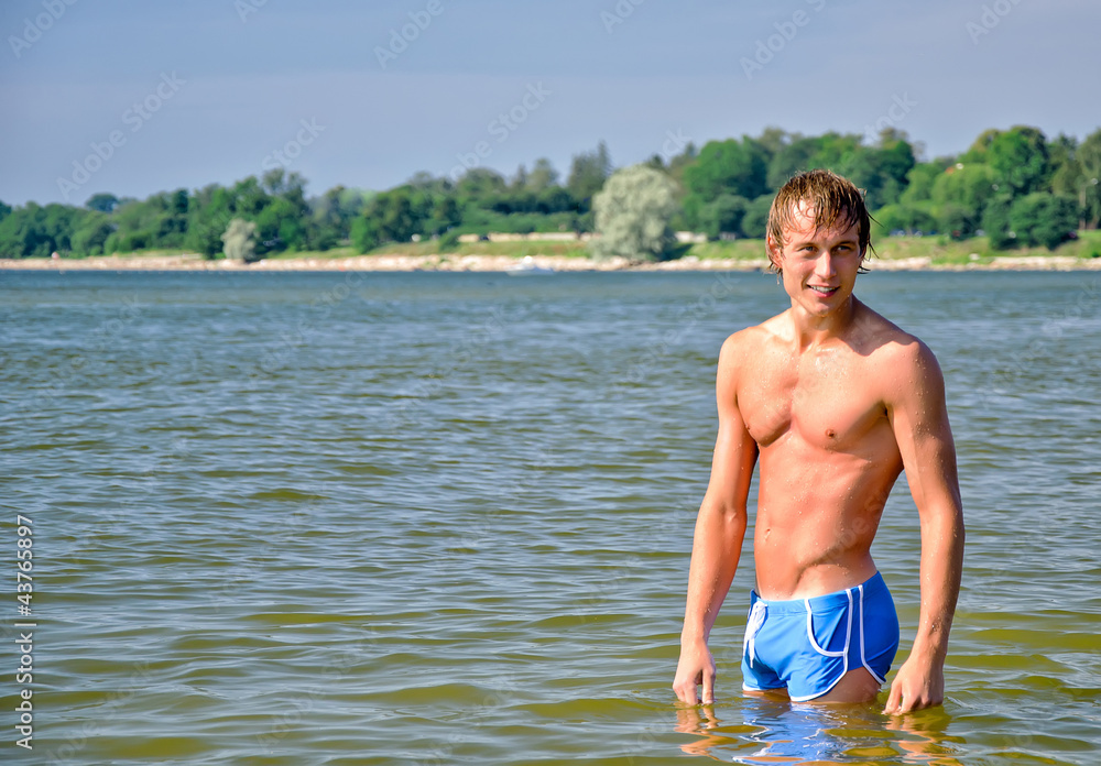 Semi nude handsome man standing in the sea