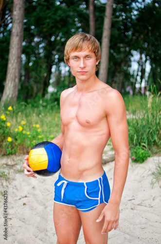 Young man posing with the ball on the beach
