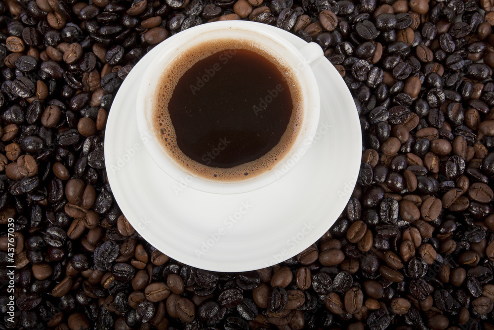 Fototapeta premium Cup of black coffee on a saucer on roasted coffee beans 