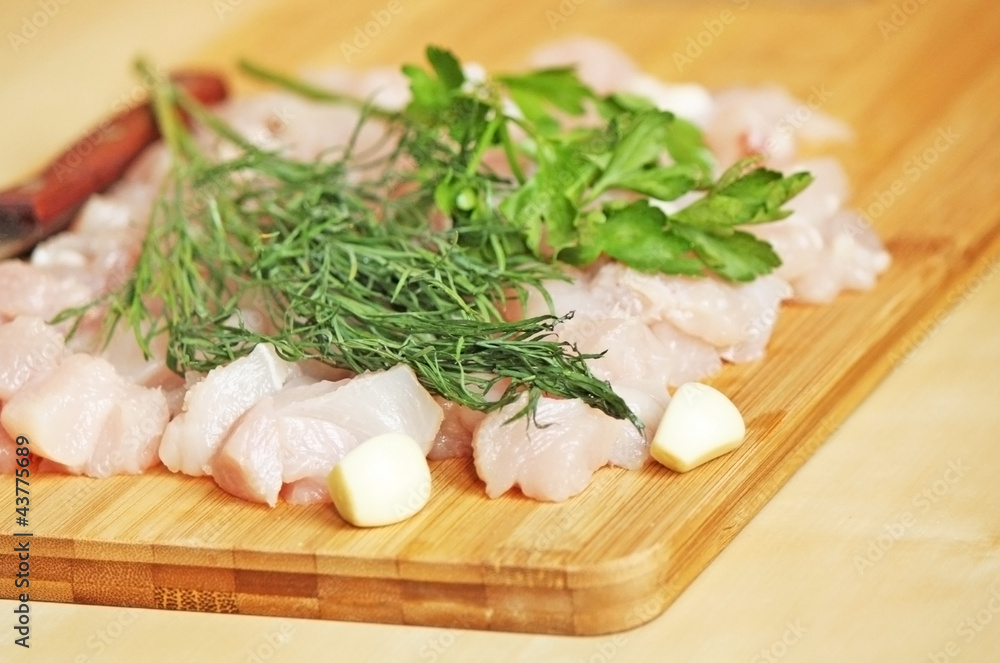 Cutted chicken fillet with parsley ang garlic and a knife Cutted chicken fillet with parsley ang garlic and a knife