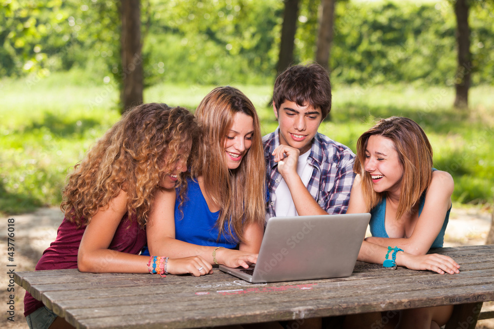 Group of Teenage Students at Park with Computer and Books Group of Teenage Students at Park with Computer and Books