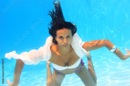 Woman wearing a white shirt swimming underwater