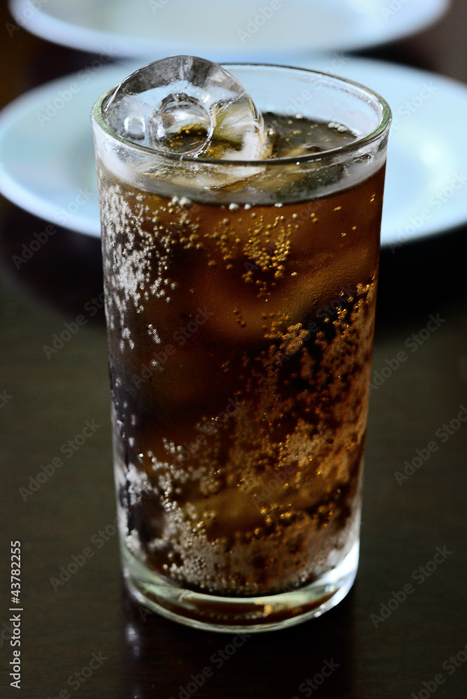 Cola into a glass with ice cubes Cola into a glass with ice cubes