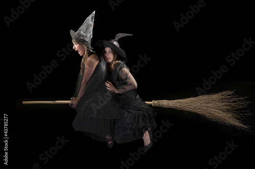 two scared witches flying on a broom