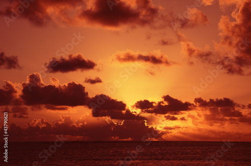 Sun setting behind dark Clouds over South Pacific Ocean