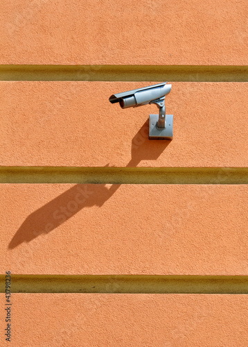 CCTV camera surveillance on the striped pink stucco wall