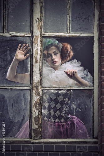 A lonely pierrot woman behind the glass photo