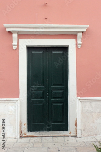 green painted wood door with pink and white walls and overhead mantle