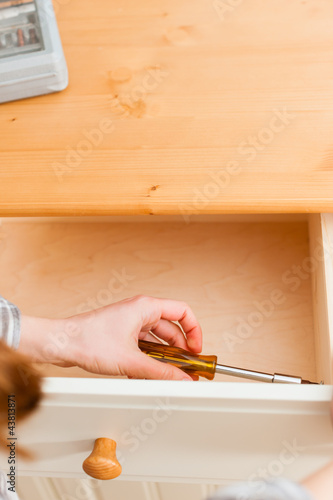 Junge Frau baut Schrank auf oder ab photo