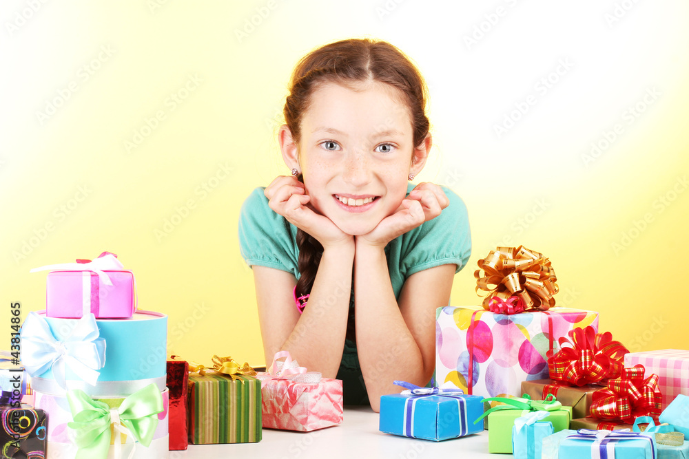 Little girl with gifts on yellow background Little girl with gifts on yellow background