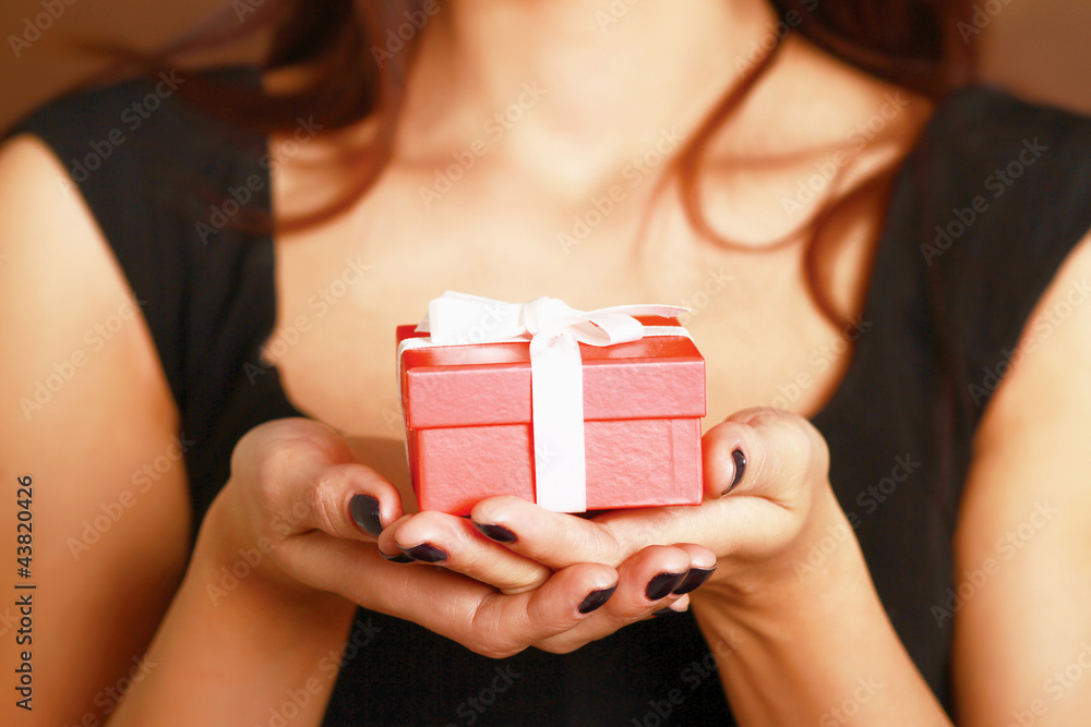 Female hand holding gift box isolated on red background Female hand holding gift box isolated on red background