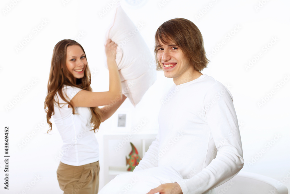 Obraz premium Young couple fighting with pillows