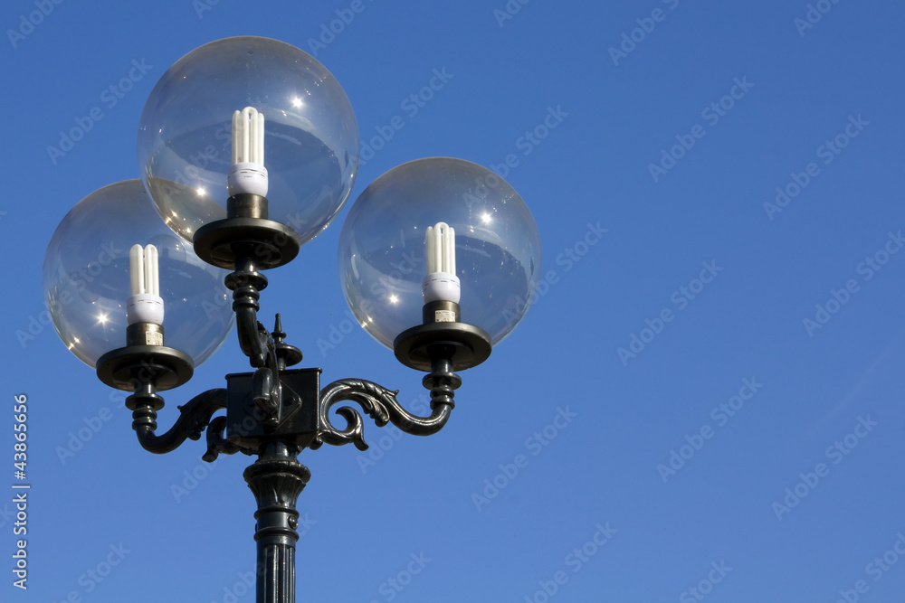Triple street lighter with energy saving lamps against blue sky Triple street lighter with energy saving lamps against blue sky