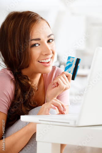 joyful young teenager shopping online with a credit card and lap