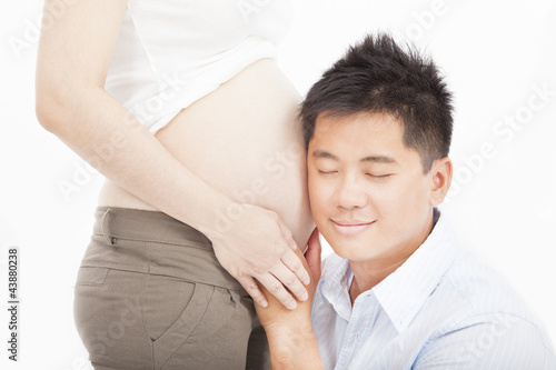 asian father listening to her pregnant wife's tummy