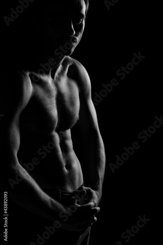 Black and white image of shirtless muscular man posing