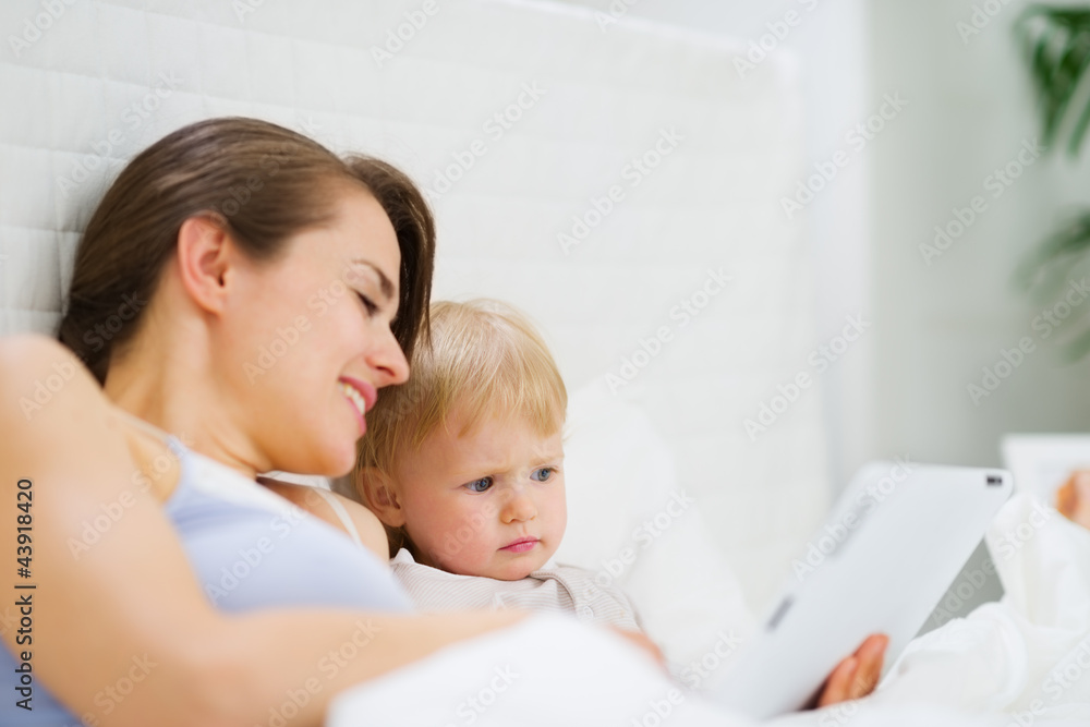 Young mother showing baby something in tablet PC Young mother showing baby something in tablet PC
