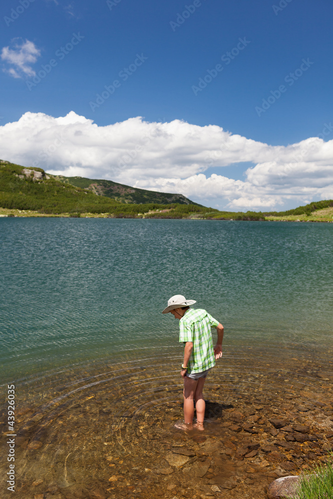 Child with hat, barefoot in a lake Child with hat, barefoot in a lake