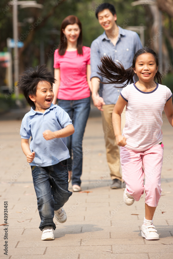 Chinese Family Walking Through Park With Running Children Chinese Family Walking Through Park With Running Children