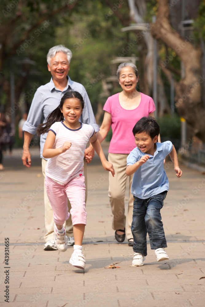 Chinese Grandparents Walking Through Park With Running Grandchil Chinese Grandparents Walking Through Park With Running Grandchil