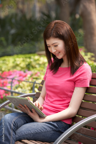 Young Chinese Woman Using Digital Tablet Whilst Relaxing