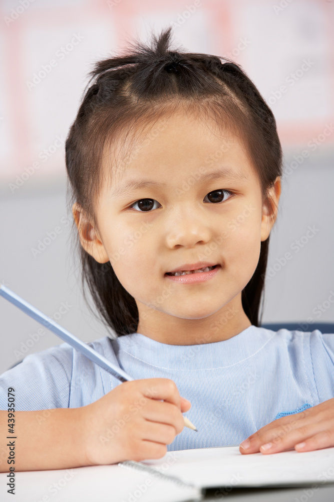 Female Student Working At Desk In Chinese School Classroom Female Student Working At Desk In Chinese School Classroom