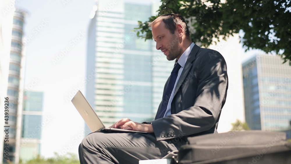 Young handsome businessman working on laptop in the city