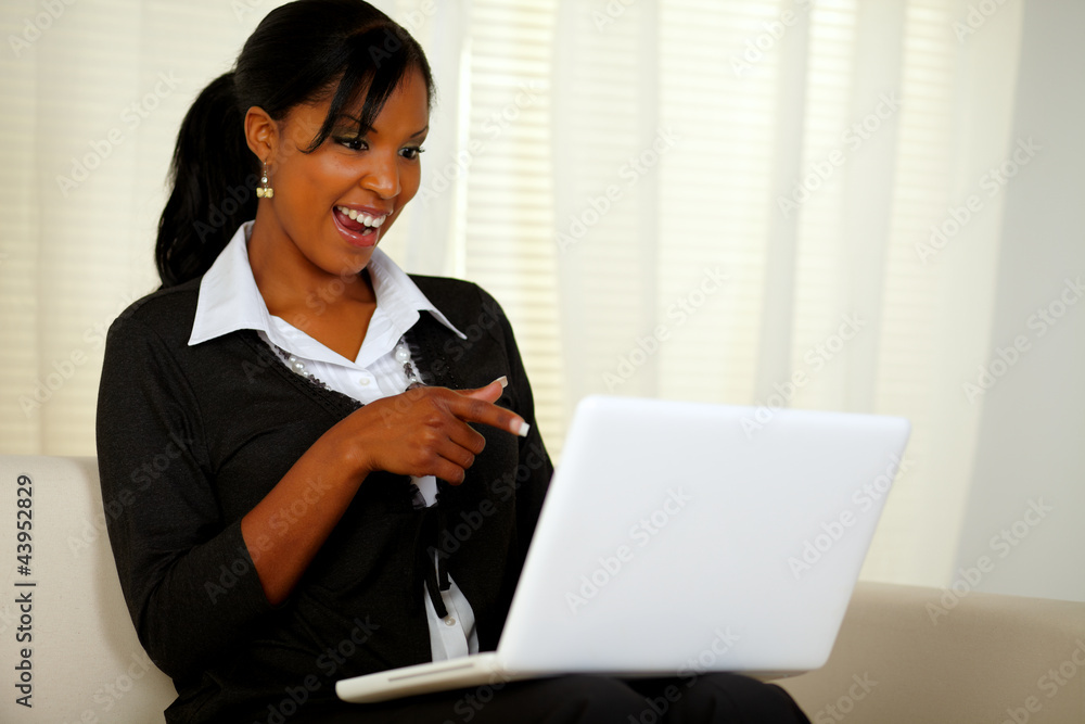 Smiling woman on black suit pointing to laptop Smiling woman on black suit pointing to laptop