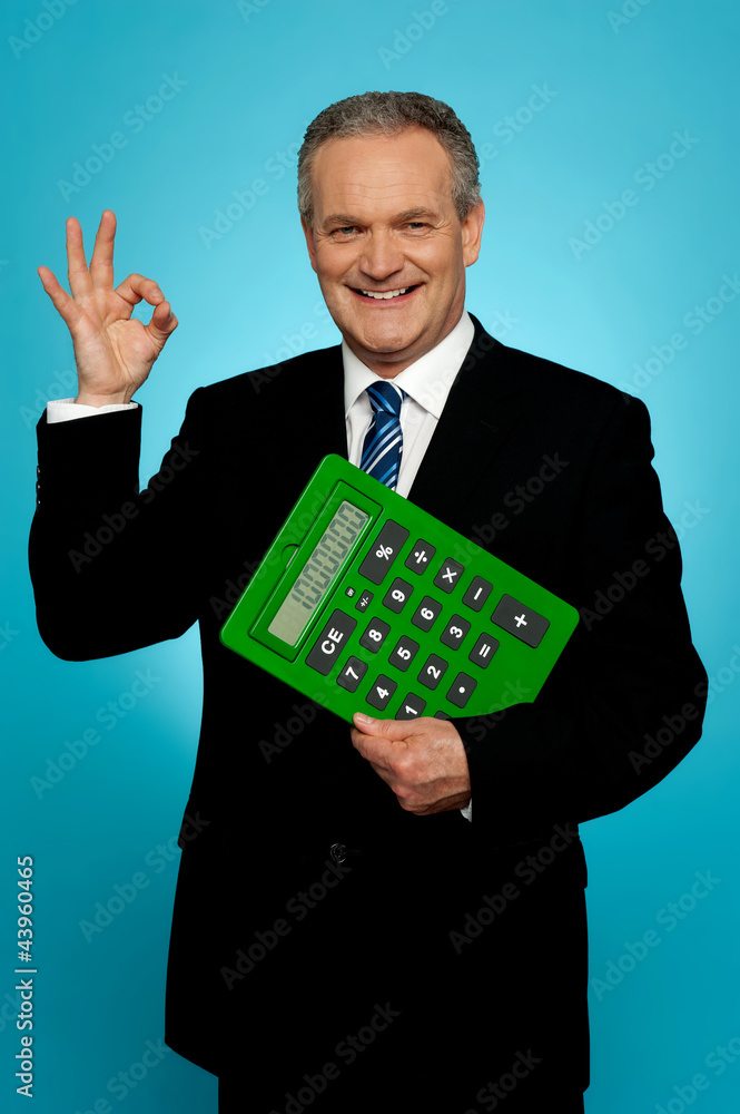 Confident executive holding calculator and gesturing okay sign