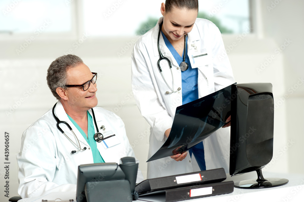 Team of two doctors reviewing x-ray report Team of two doctors reviewing x-ray report