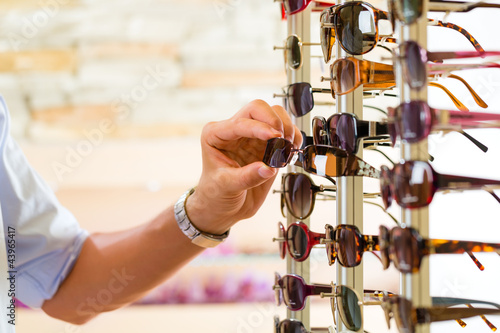 Junger Mann beim Optiker kauft Brille photo