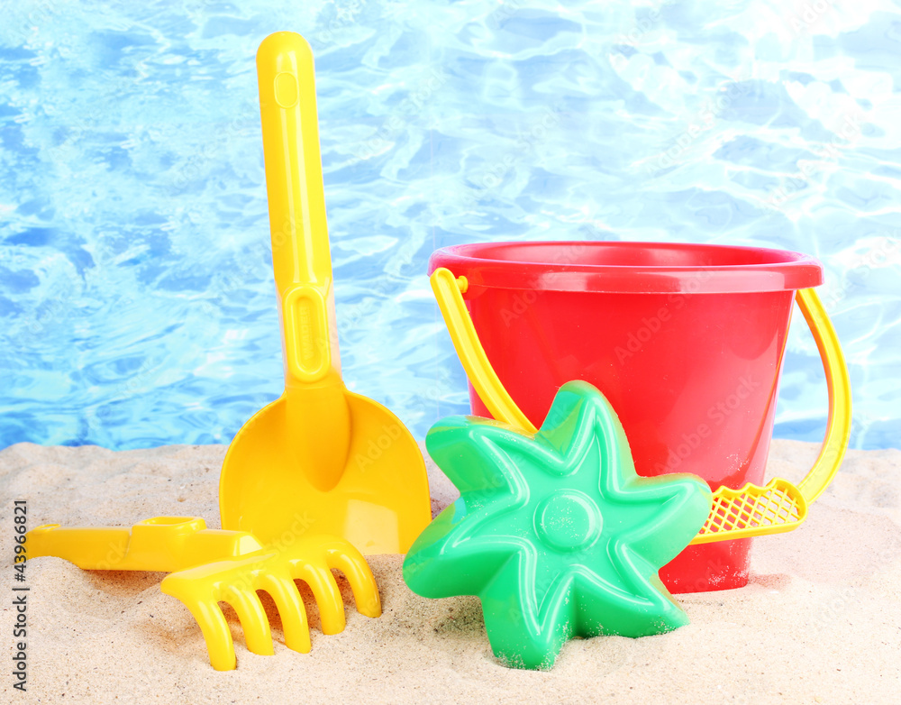 Children's beach toys on sand on water background Children's beach toys on sand on water background