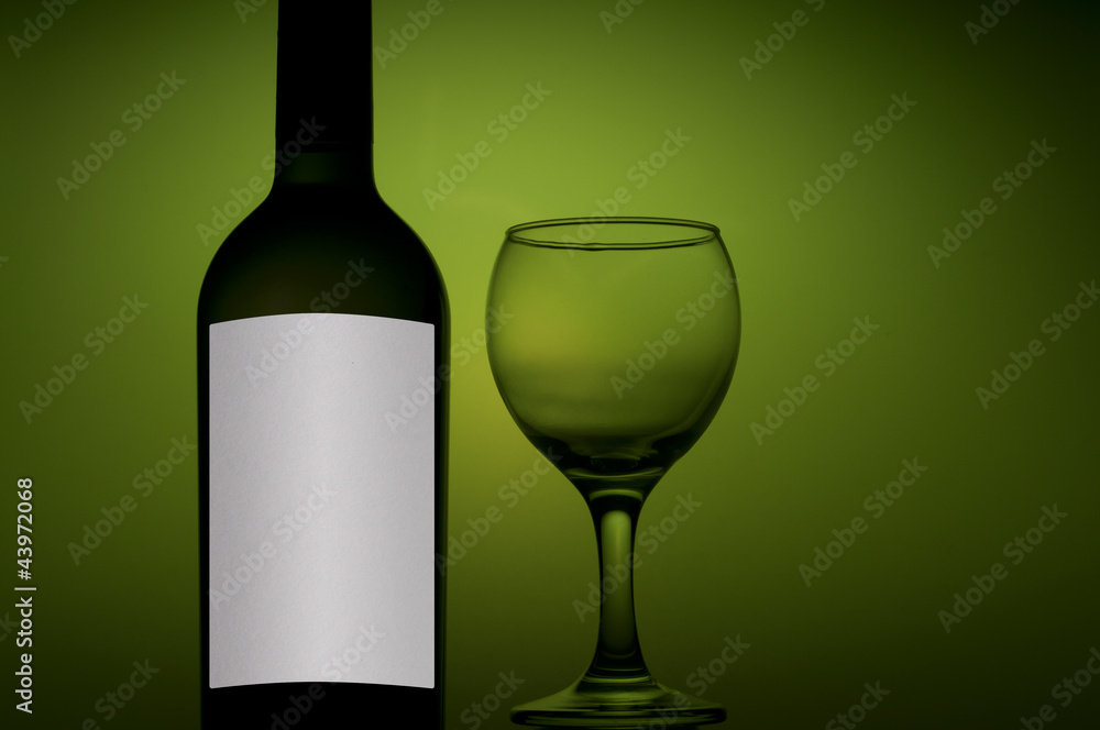 bottle and glass with white wine on green background