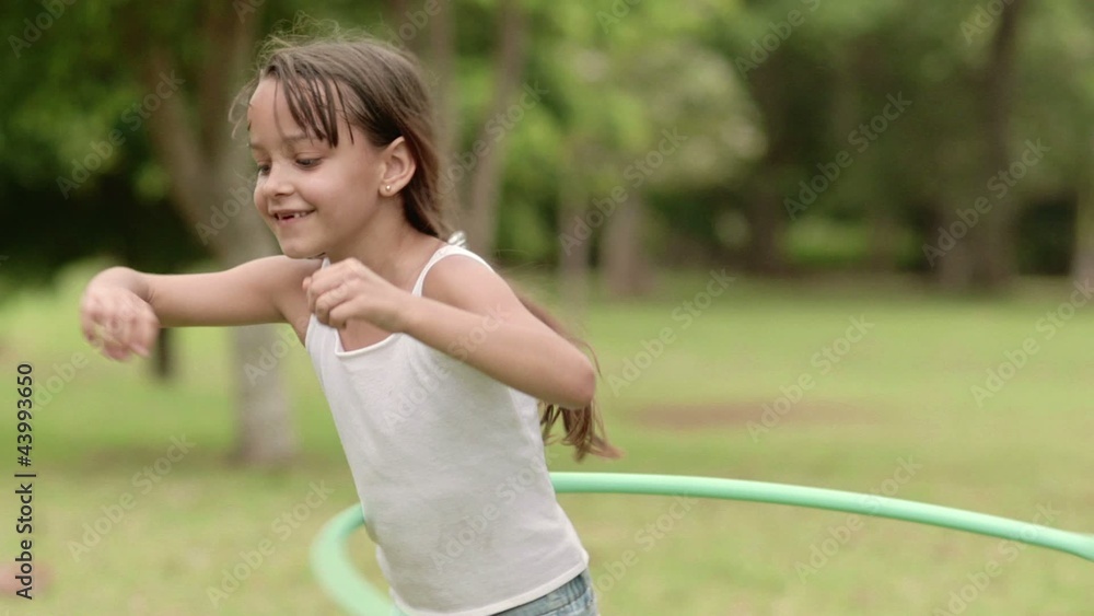 Happy little girl playing hula hoop in park. Slow motion Happy little girl playing hula hoop in park. Slow motion