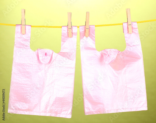 Cellophane bags hanging on rope on green background © Africa Studio