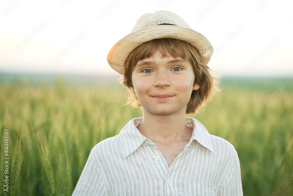 Happy boy in the hat among the wheat field