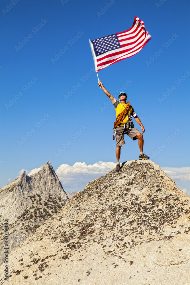 Fototapeta premium Climber waves flag on mountain peak.