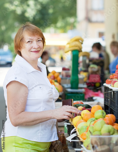 Mature woman  chooses fruits photo