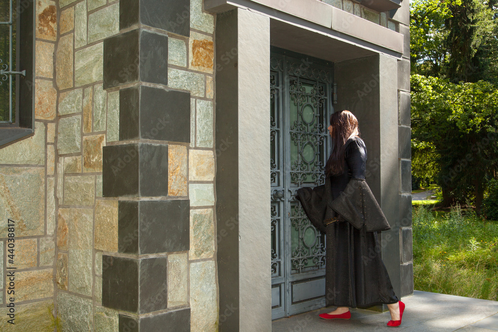 Eine schwarz gekleidete Frau steht vor einem Mausoleum Eine schwarz gekleidete Frau steht vor einem Mausoleum