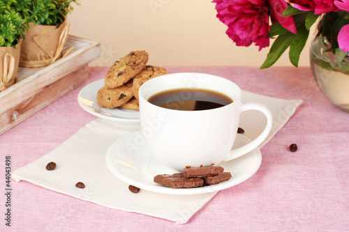 cup of coffee, cookies, chocolate and flowers on table in cafe
