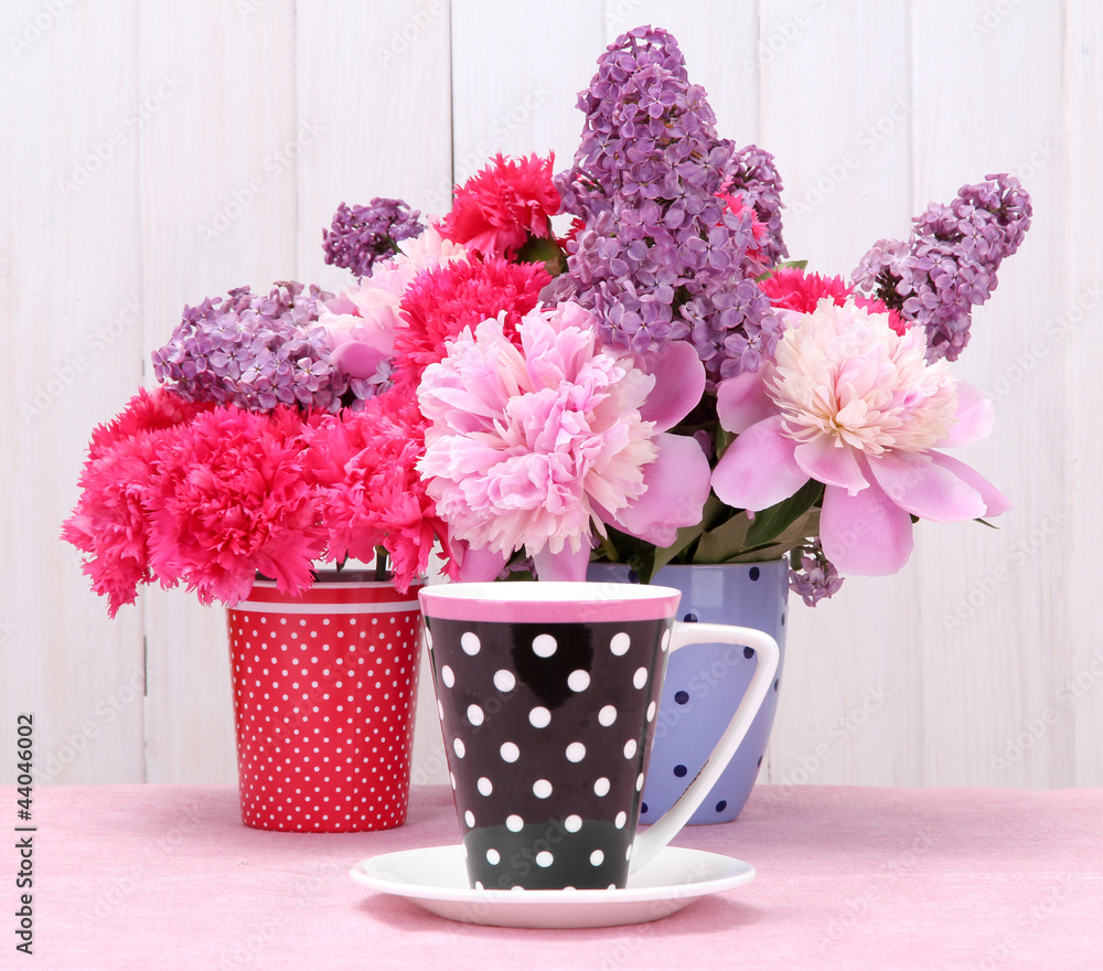 Obraz spring flowers and cup on table on white wooden background