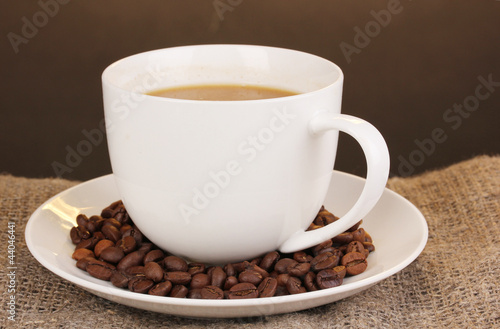 Cup of coffee on sacking on brown background © Africa Studio