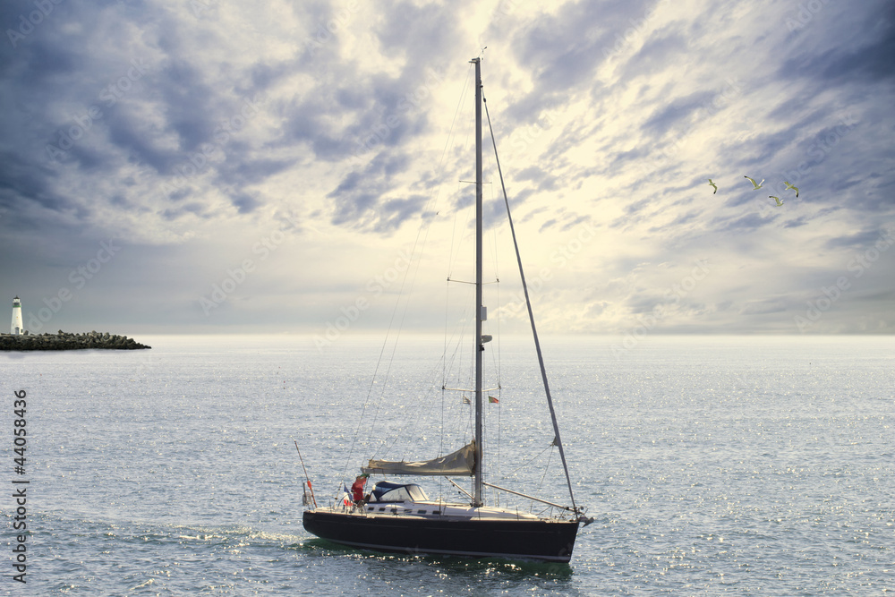 blue sailboat leaving the harbor